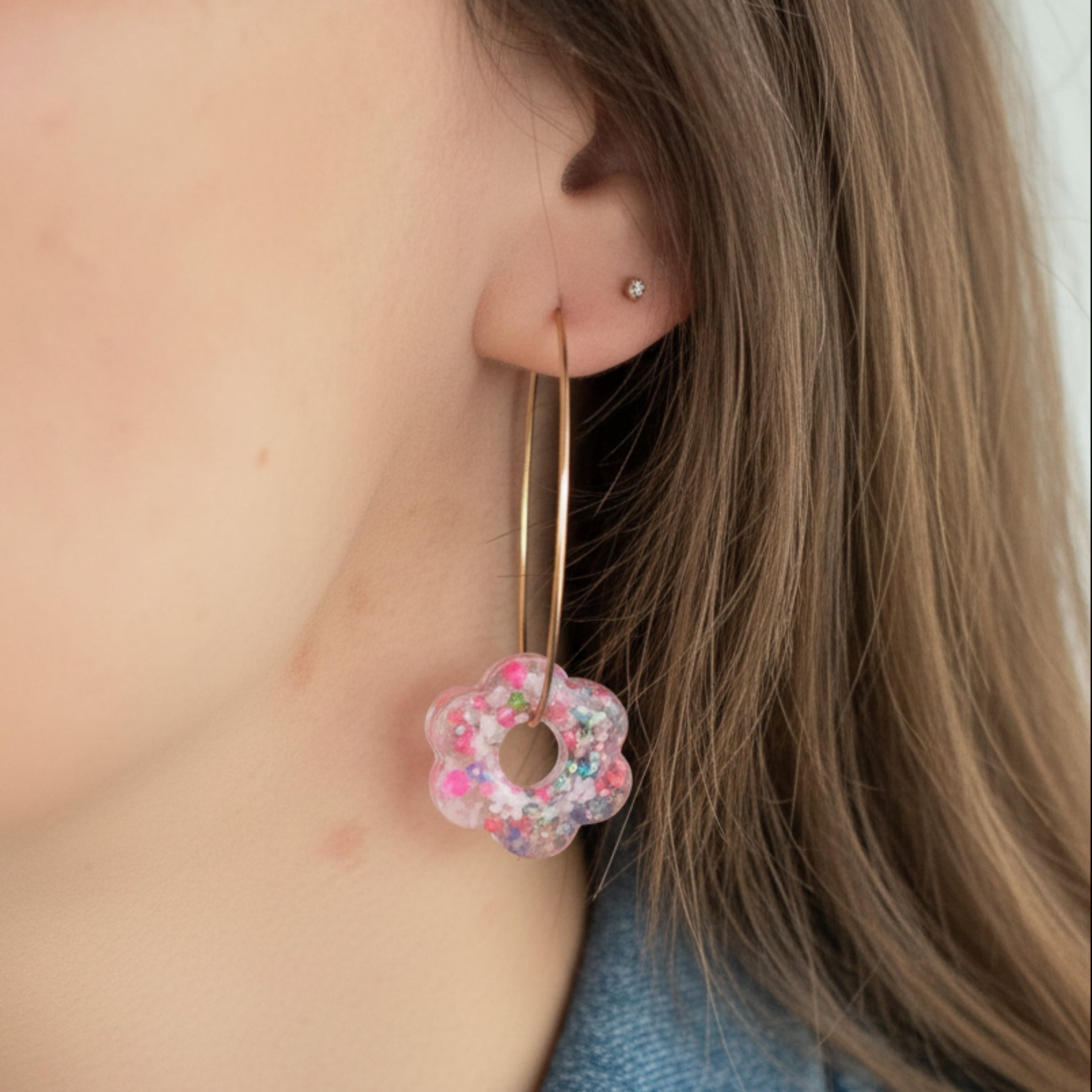 Pampille fleur en résine faite main portée sur créole dorée, finition transparente multicolore