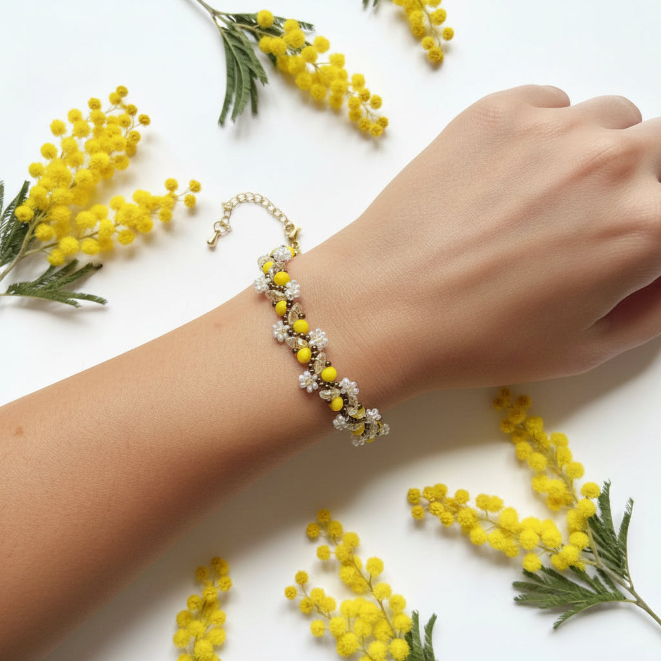 Bracelet Mimosa tissé main porté au poignet, perles verre facettes jaune soleil et rocailles dorées, fermoir doré ajustable
