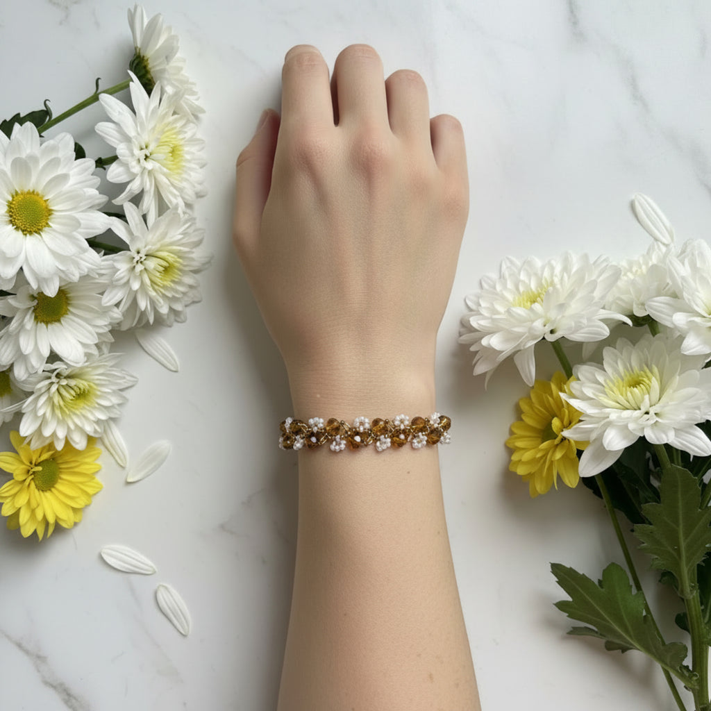 Bracelet Chrysanthème tissé main porté au poignet, perles verre facettes ambre doré et rocailles blanc cristal, fermoir doré ajustable