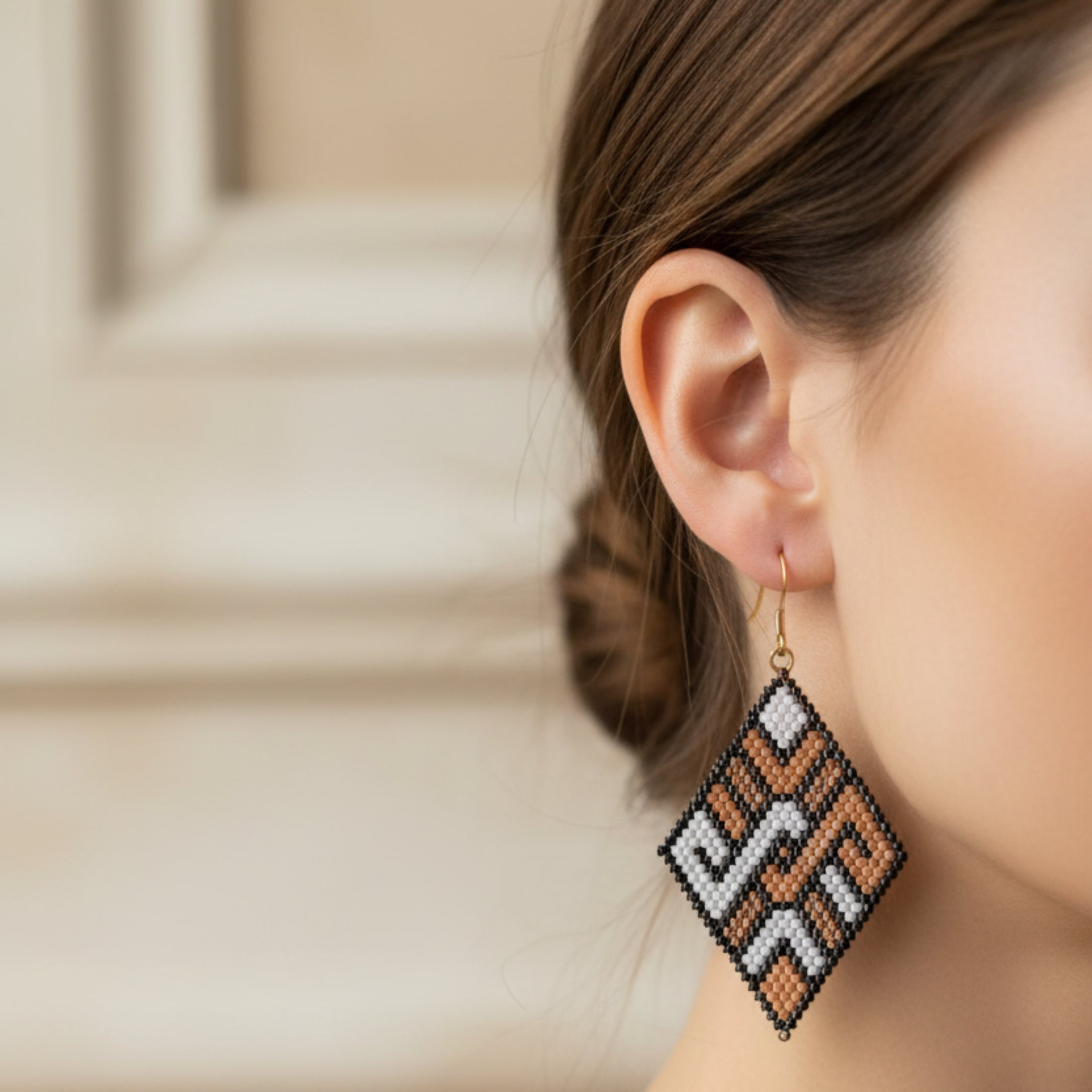 Boucles d'oreilles Kenza ÔParis portées, tissage Miyuki Delica chevron noir et cuivré, longueur 7 cm, finition crochet doré.