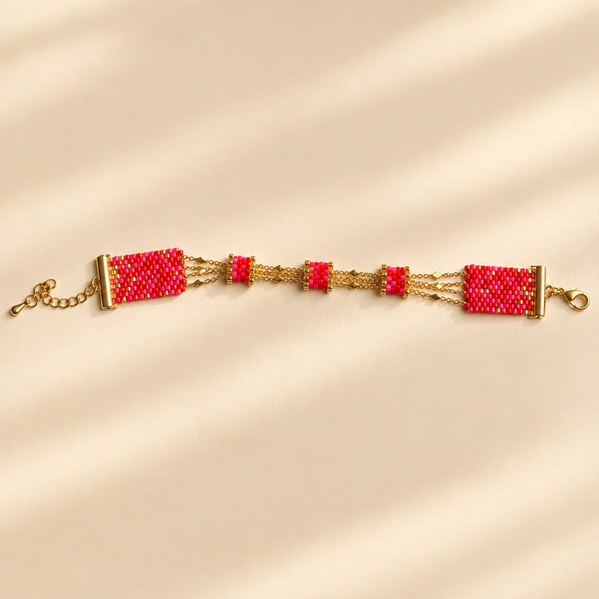 Bracelet Rosalia fait main en perles Miyuki roses, rouges et dorées, chaînes en acier inoxydable et chaînette d’extension.
