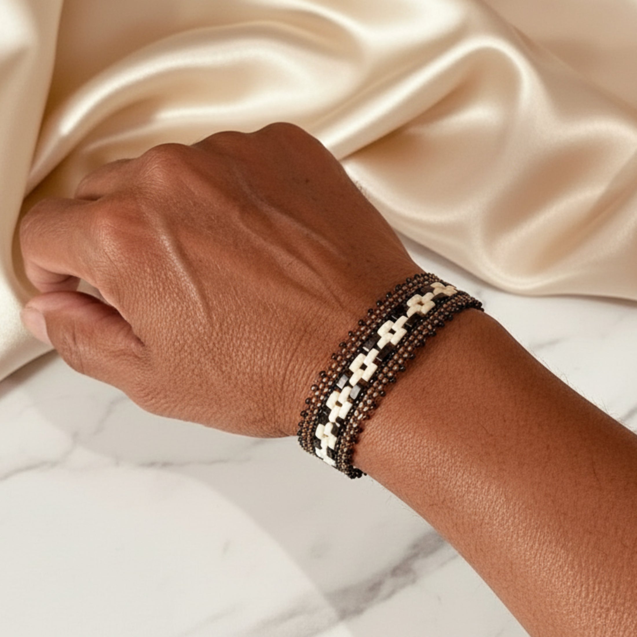Femme portant le bracelet précieux ÔParis au poignet, bijou fait main en perles Miyuki dorées
