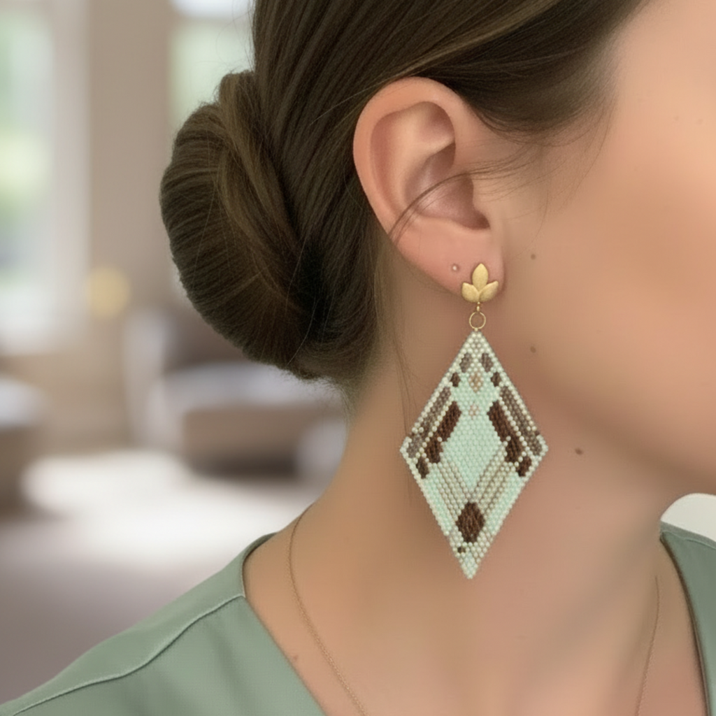 Boucles d'oreilles losange en perles Miyuki vert menthe, marron et blanc, monture puce dorée motif feuille, port à l'oreille.
