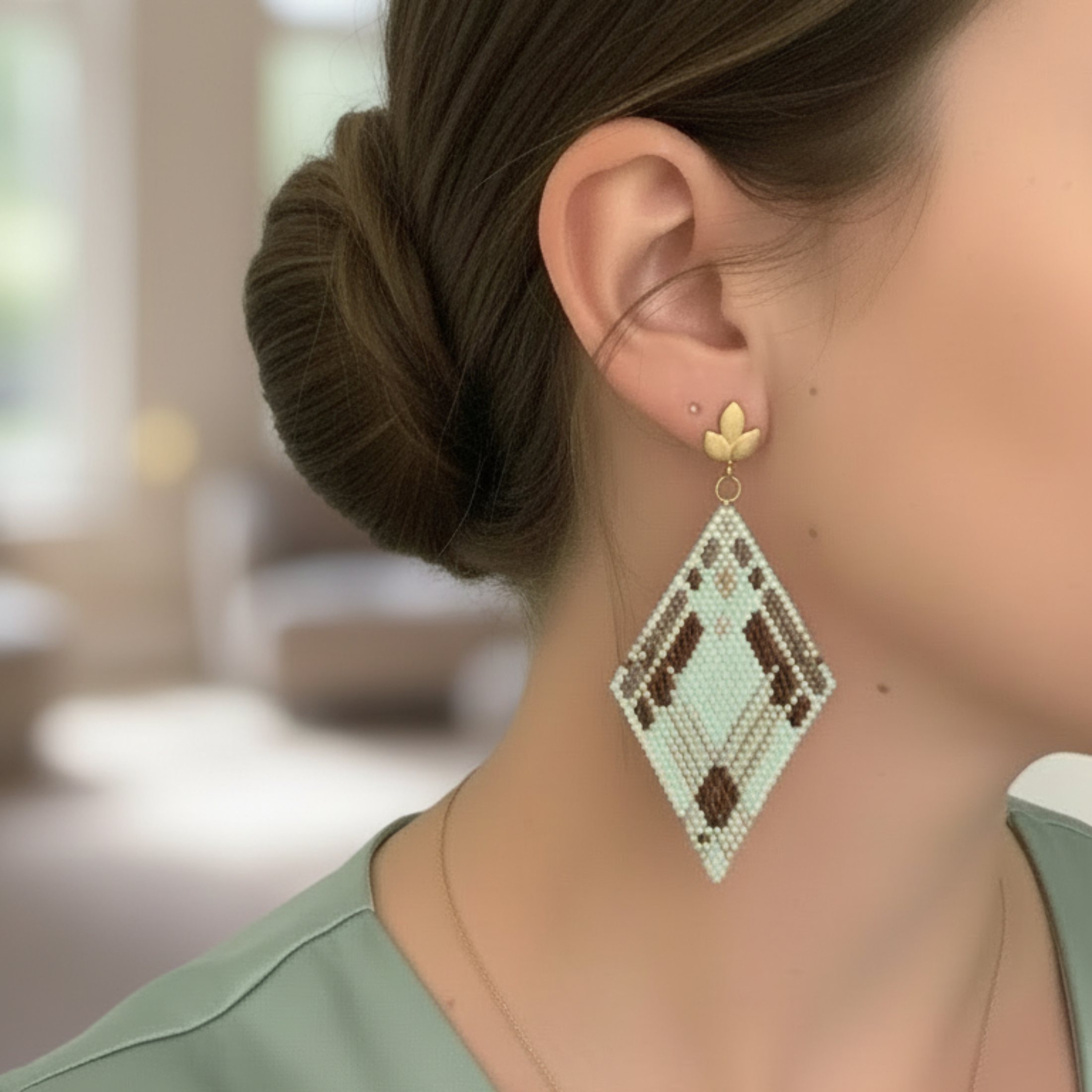 Boucles d'oreilles losange en perles Miyuki vert menthe, marron et blanc, monture puce dorée motif feuille, port à l'oreille.
