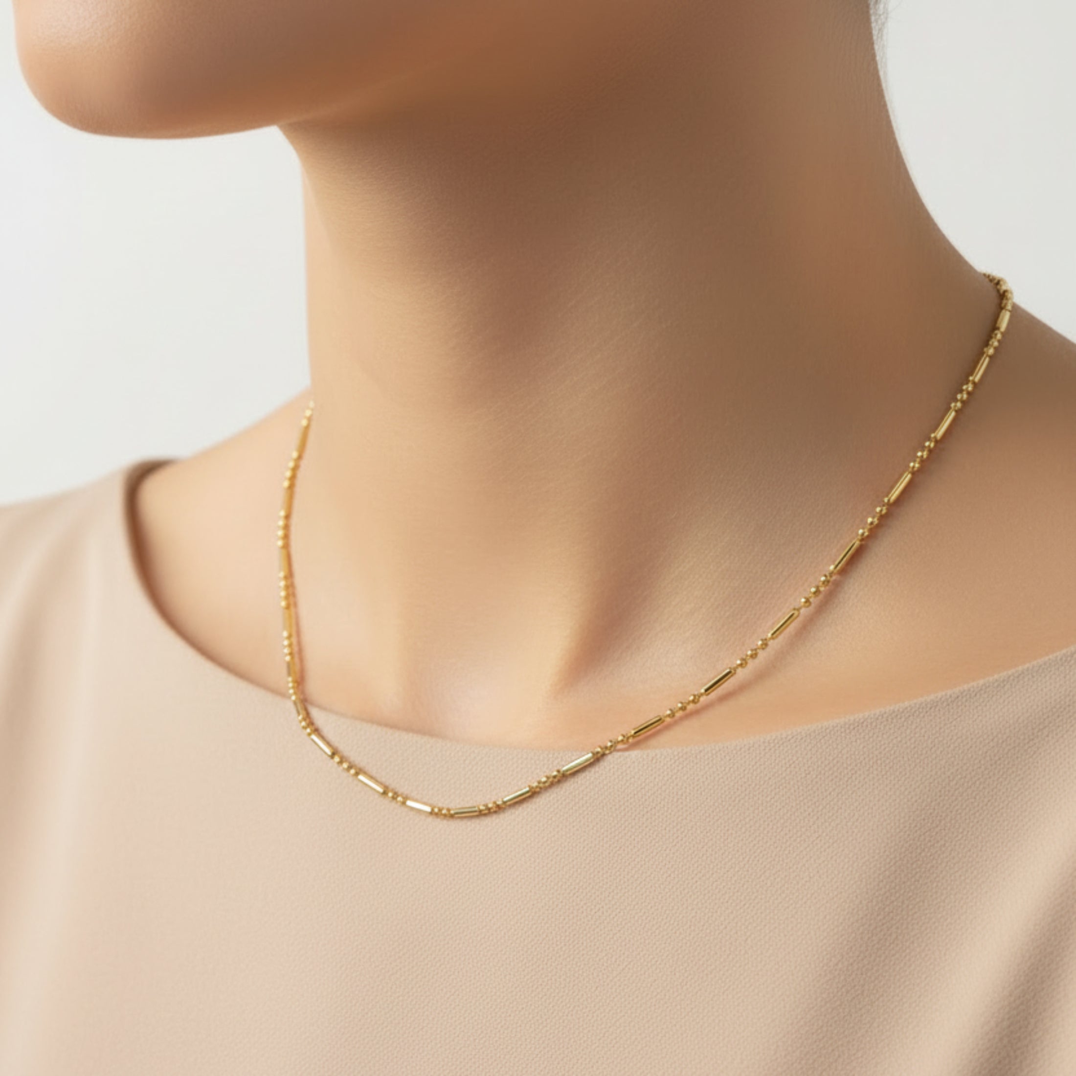Collier Céleste ÔParis – Chaîne fine dorée mailles alternées portée au cou sur haut beige